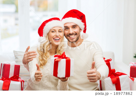 happy couple with christmas gifts and thumbs up 18977862