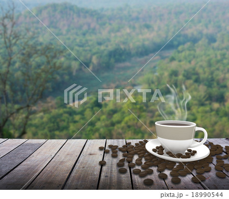 Cup with coffee on table over mountains landscape Cup with coffee on table over mountains landscape 18990544