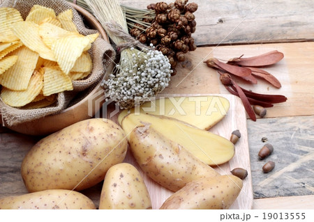 Potato chip and fresh potatoes on wood background Potato chip and fresh potatoes on wood background 19013555