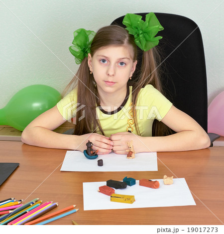 Girl sitting at a table with plasticine Girl sitting at a table with plasticine 19017273