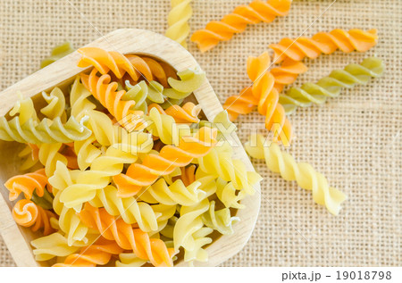 Raw italian colorful pasta, macaroni in wood cup. 19018798