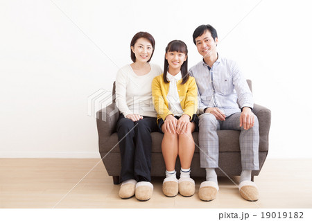ソファーに座る幸せな家族3人イメージの写真素材