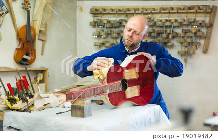 Craftsman holding unfinished guitar 19019882