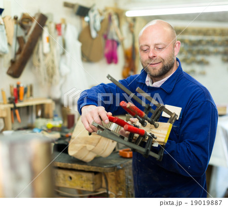 craftsman working with unfinished guitar craftsman working with unfinished guitar 19019887