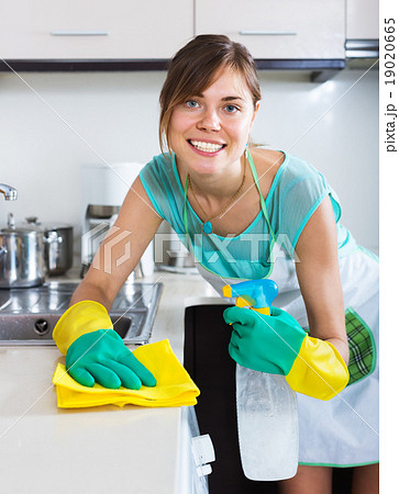 Adult girl dusting surfaces in kitchen Adult girl dusting surfaces in kitchen 19020665