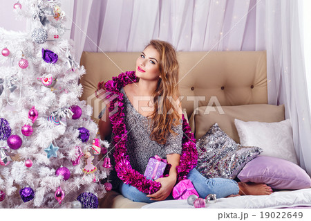Girl sits on a couch near Christmas tree. Girl sits on a couch near Christmas tree. 19022649