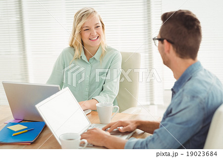 Smiling woman looking at man while sitting on chair 19023684
