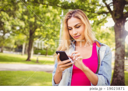 Smiling woman using smartphone in park 19023871