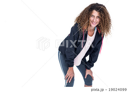Happy young woman bending with hand on knee 19024099