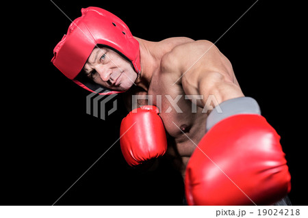 Portrait of boxer with gloves punching against black background Portrait of boxer with gloves punching against black background 19024218