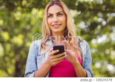 Smiling woman looking away while touching smartphone Smiling woman looking away while touching smartphone 19024379