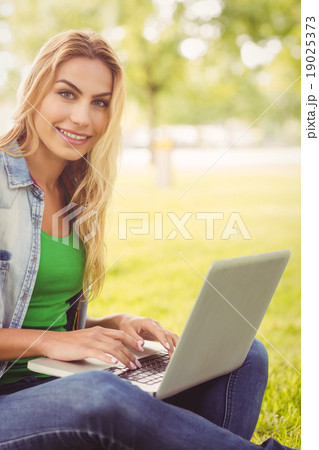 Portrait of smiling woman using laptop at park Portrait of smiling woman using laptop at park 19025373