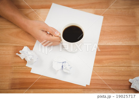 Man holding black coffee cup on paper at desk 19025717