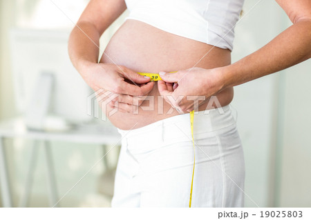Midsection of woman measuring abdomen 19025803