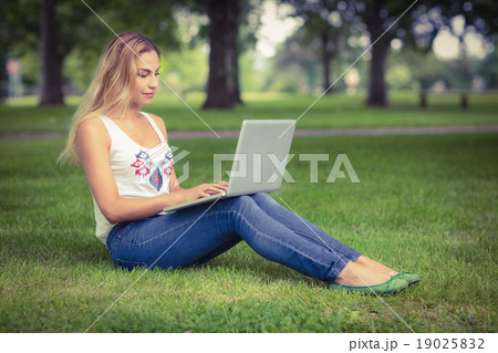 Full length of woman using laptop at park Full length of woman using laptop at park 19025832
