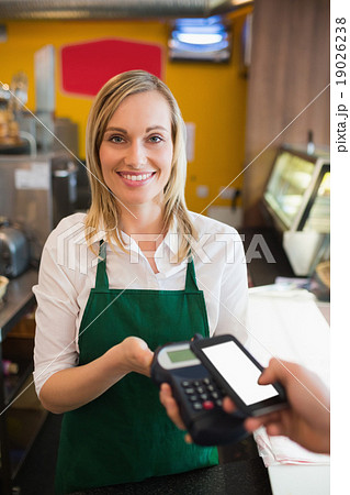 Portrait of female worker accepting payment through NFC Portrait of female worker accepting payment through NFC 19026238