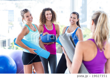 Women smiling looking at each other in fitness studio 19027351