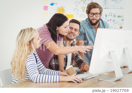 Business professionals discussing at computer desk 19027709