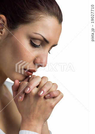 Close-up of woman praying with joining hands and eyes closed 19027710