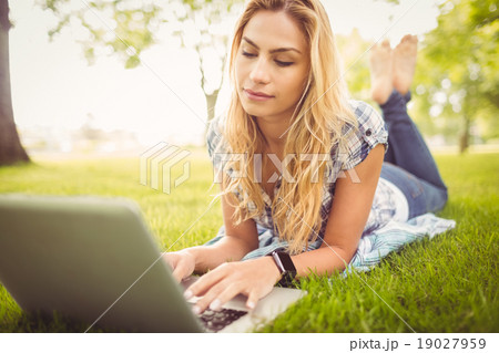 Woman using laptop while lying on grass Woman using laptop while lying on grass 19027959