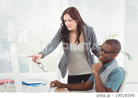 Businesswoman holding eyeglasses while looking at computer Businesswoman holding eyeglasses while looking at computer 19028590