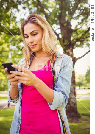 Happy woman using smartphone in park Happy woman using smartphone in park 19028981