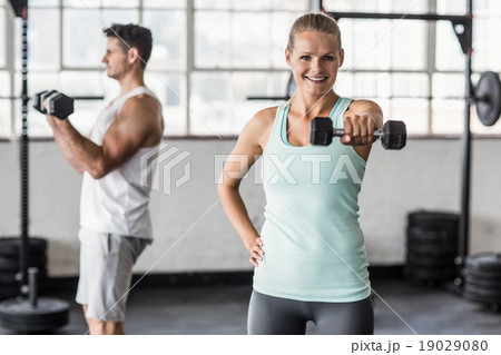 couple exercising with dumbbells in gym 19029080