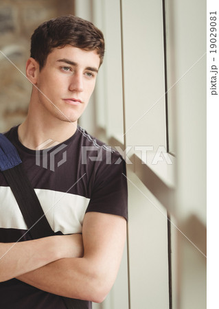 Close-up of thoughtful male student leaning on window 19029081