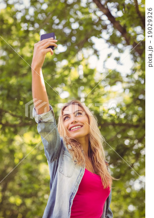 Low angle view of smiling woman taking selfie Low angle view of smiling woman taking selfie 19029326