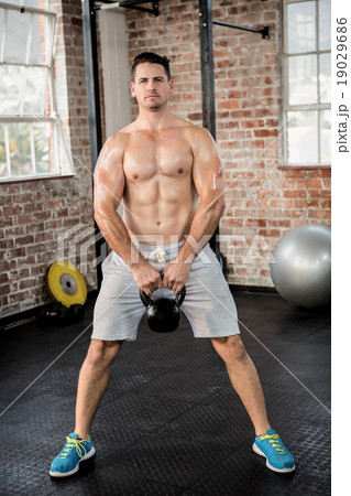 Portrait of shirtless man lifting kettlebell Portrait of shirtless man lifting kettlebell 19029686