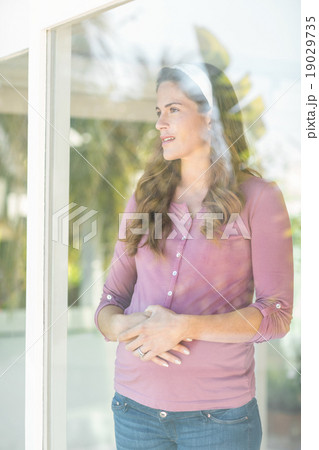 Happy woman standing by glass window Happy woman standing by glass window 19029735
