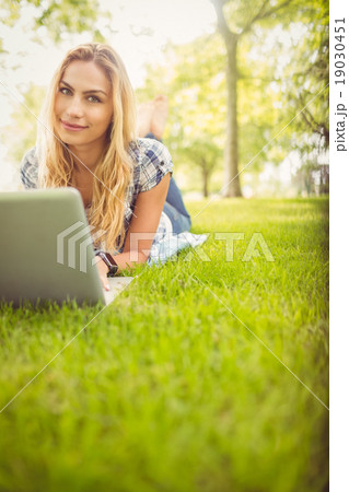 Portrait of smiling woman using laptop while lying on grass Portrait of smiling woman using laptop while lying on grass 19030451