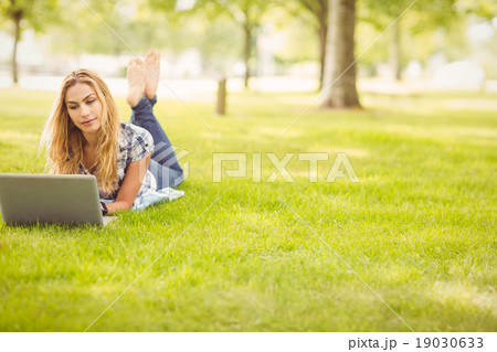 Full length of woman using laptop while lying on grass Full length of woman using laptop while lying on grass 19030633
