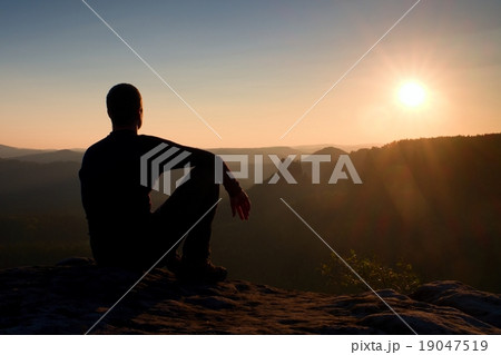 Hiker take relaxing on a rock and enjoying sunset 19047519