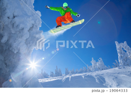 Snowboarder jumping against blue sky Snowboarder jumping against blue sky 19064333