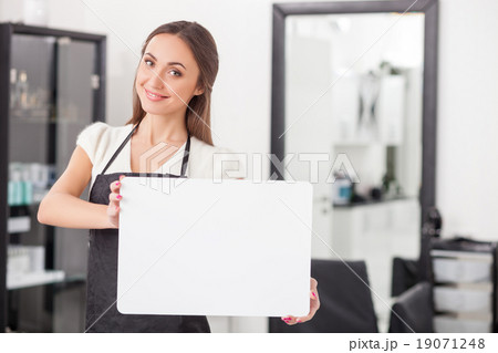 Cheerful female hairdresser is showing a placard 19071248
