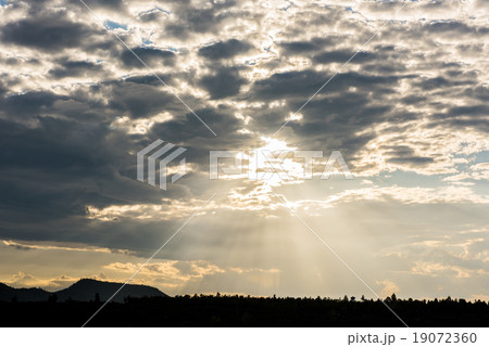 Crepuscular sun rays during sunset over the hill 19072360