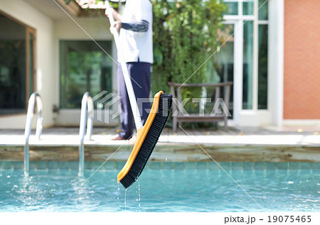 Mna is cleaning a swimming pool with a brush 19075465