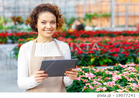 Smiling florist holding a tablet. 19077241