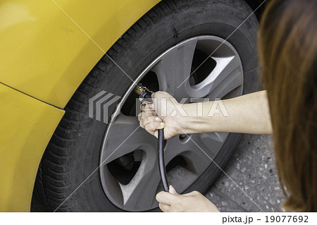Hand filling air into a car tire, close up. 19077692