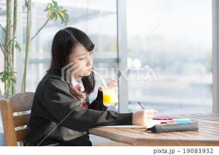 学校帰りにカフェで勉強する女子校生の写真素材