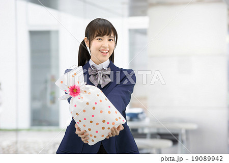 プレゼントを抱えて立っている制服姿の女子高生のポーズ 19089942