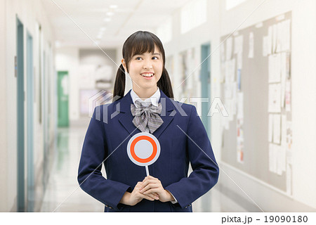学校の廊下で○×サインを持って立っている制服姿の女子高生のポーズ 19090180