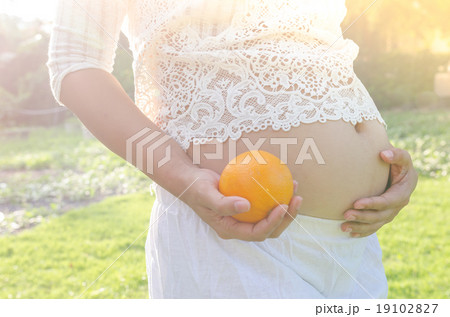 Close up pregnant belly holding oranges in hand Close up pregnant belly holding oranges in hand 19102827