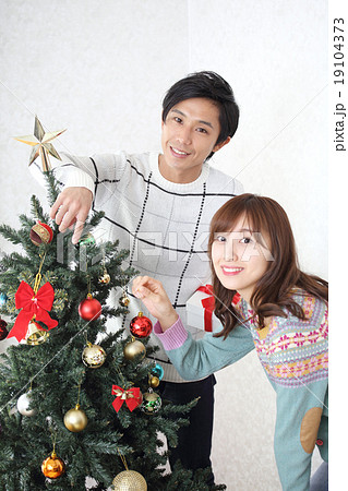 クリスマスツリーを飾るカップルの写真素材