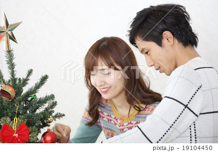 クリスマスツリーを飾るカップル 19104450