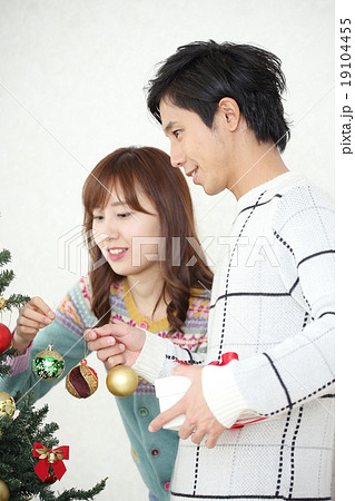 クリスマスツリーを飾るカップル 19104455