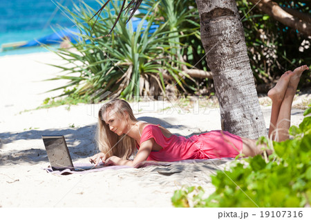 Blond girl with a laptop on tropical beach Blond girl with a laptop on tropical beach 19107316