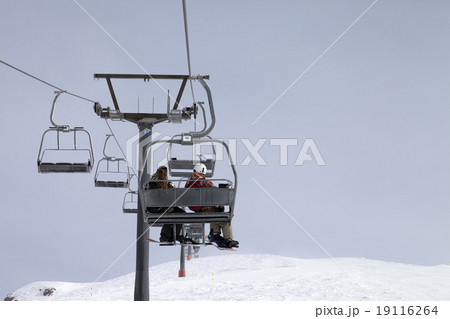 Snowboarders on chair-lift and ski slope at gray Snowboarders on chair-lift and ski slope at gray 19116264