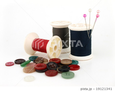 a spool of thread, needle and button 19121341